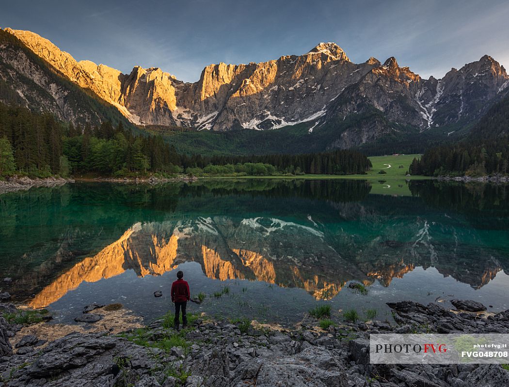 Tourist looking the Fusine lake and Mangart mountain group at sunset, Tarvisio, Julian alps, Friuli Venezia Giulia, Italy, Europe